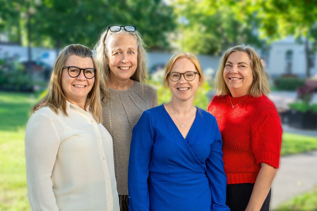 Fyra kvinnor i glada kläder utomhus i en grönskande park.