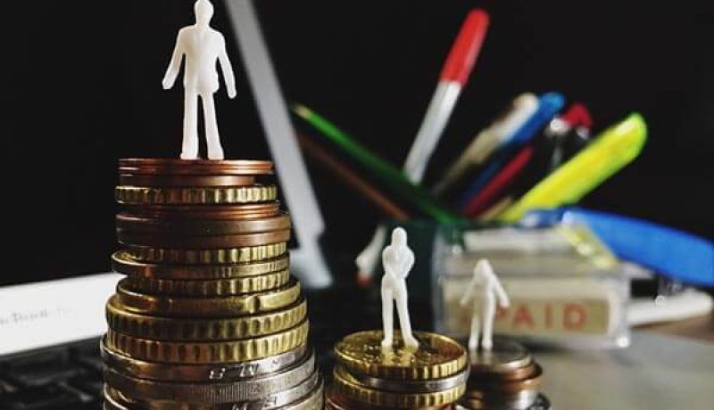 Miniatyrfigurer på staplade mynt vid en dator representerar ekonomisk tillväxt och framgång.